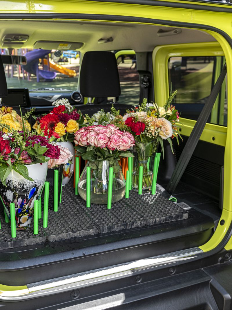 Florero con arreglo floral montado sobre base panal Transporta Seguro negra con soportes naranjas